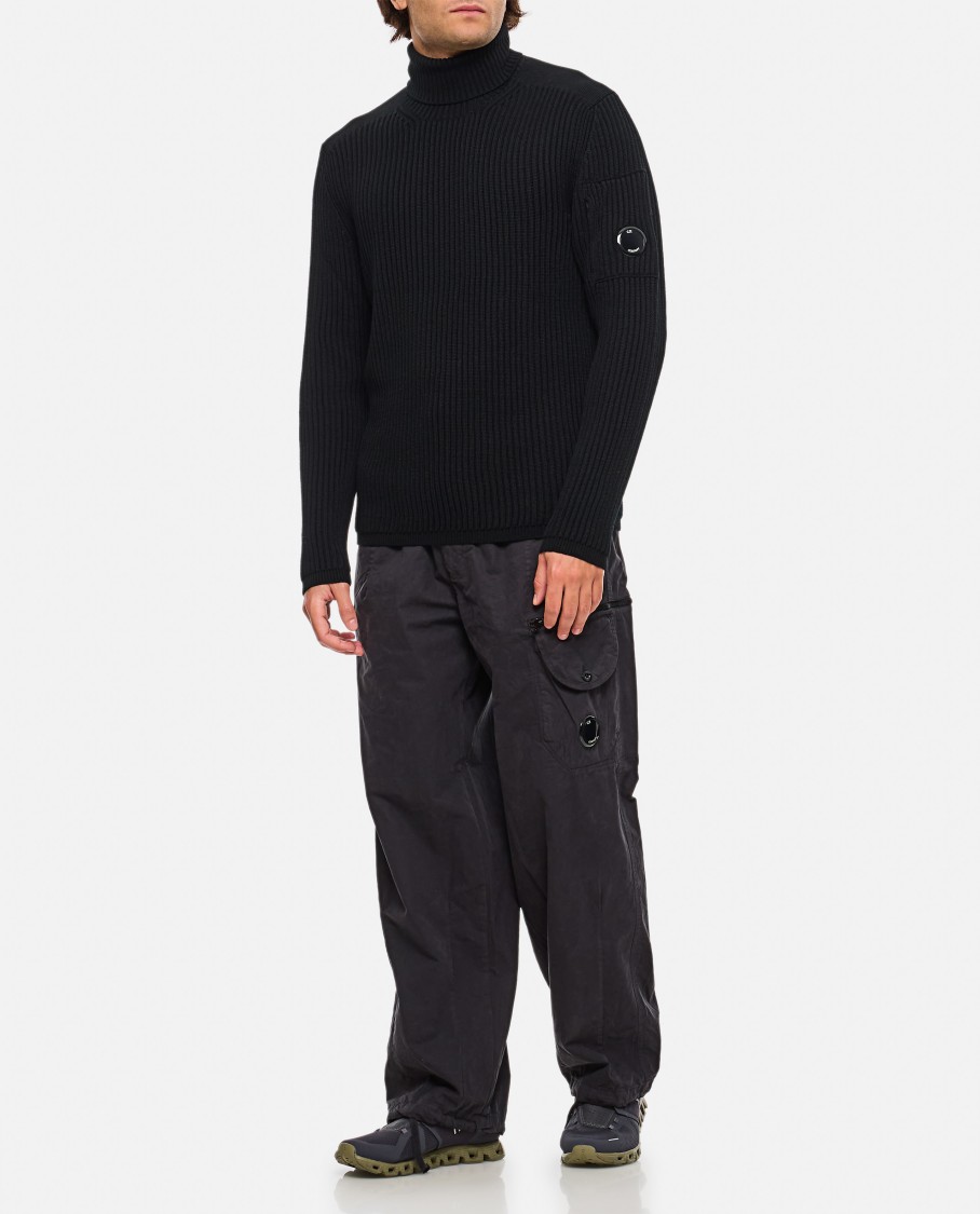 C.p. Company Ribbed Knit Roll Neck Sweater With Signature Lens Detail And Zip Pocket In Black